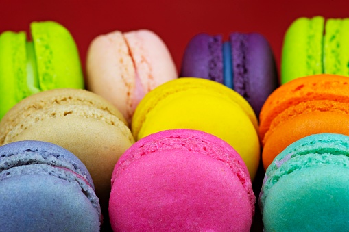 Colorful macaron snacks - red background.