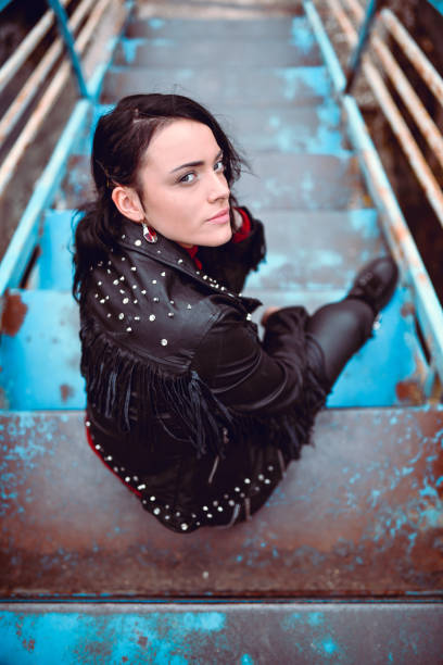 carino goth femmina in giacca di pelle seduto su gradini del ponte arrugginito fuori - rock staircases foto e immagini stock