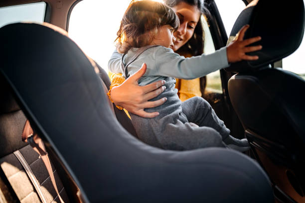 istock Mother tightening seatbelt for kind on back seat 1321728523