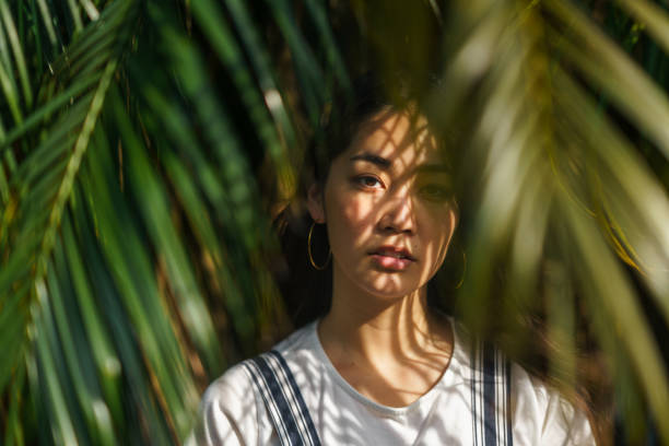 portrait de belle femme aux feuilles de palmier - forest sunbeam tree light photos et images de collection