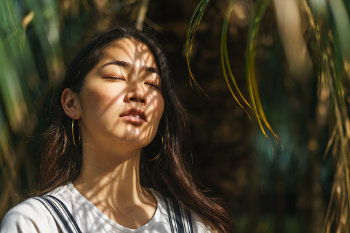 A portrait of a beautiful woman with palm tree leaves.