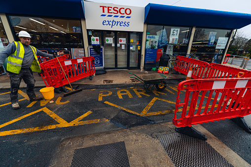 tarmac/asphalt repairs being carried out by trained workers with machinery at Tescos petrol station we ppe and health & safety equipment, all used to repair potholes and damaged surface  in Doncaster, Yorkshire