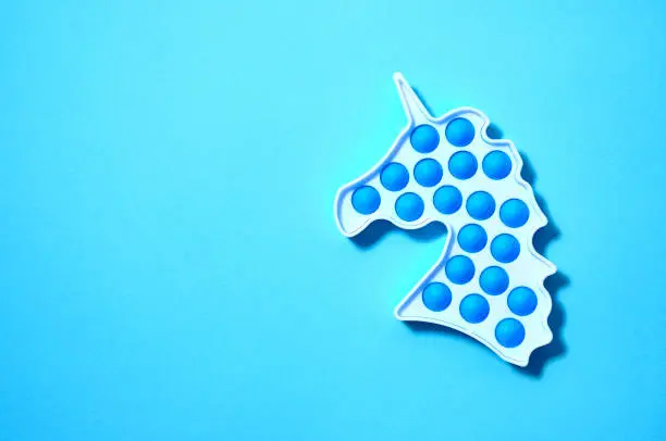 Photo of Simple dimple in form unicorn on blue background. Top view Flat lay. Copy Space