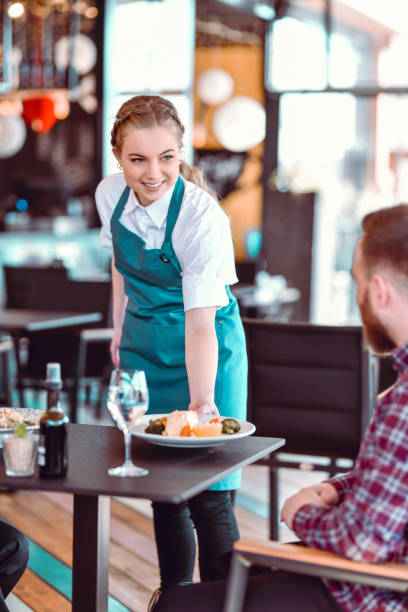istock Smiling Blond Waitress Bringing Food To Happy Guest 1321735210