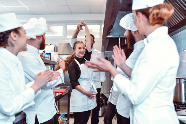 Happy Kitchen Team Encouraging Chef To Dance With Cute Waitress