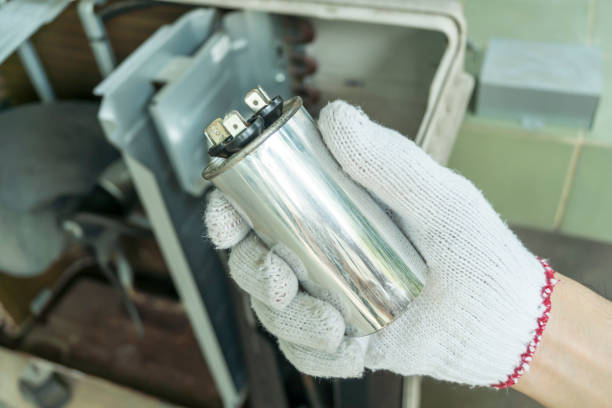 technicien installant un nouveau condensateur de climatiseur, condensateur de compresseur d’air de vérification, service de réparation d’appareils électroménagers. - condensateur photos et images de collection