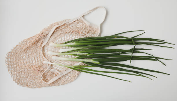 istock Young fresh green onions on white background. Zero waste shopping concept. Fresh vegetables in eco friendly bag on white table top view, flat lay. Healthy organic food 1321741164