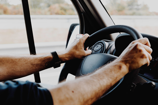 Male hands gripping the steering wheel while driving.
Conceptual of lifestyle