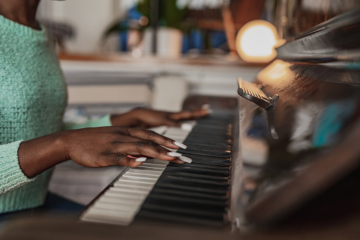 Young African American woman is playing piano at home