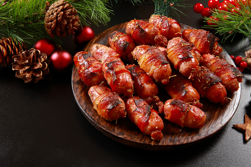 British tradition of Pigs in a Blanket, sausages (mainly Chipolatas) wrapped in Bacon, and served with Christmas Turkey or at an party or event as buffet food with cocktail sticks