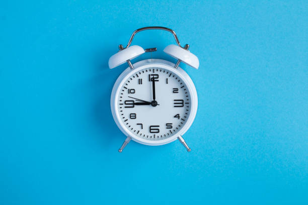 istock White alarm clock on the blue background. Top view. Close-up. 1321756462