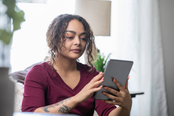 istock Young adult female reading on her digital tablet 1321757580