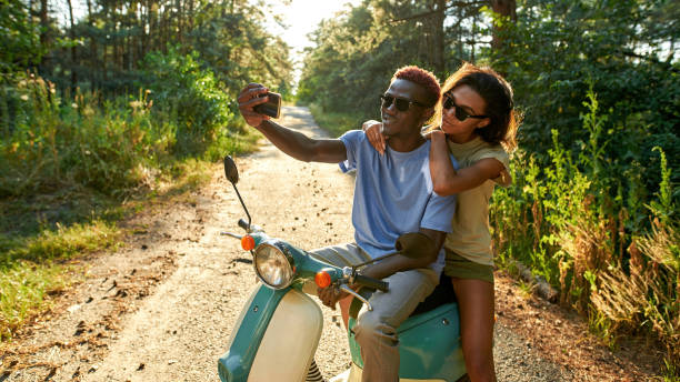 jeune couple afro-américain souriant prenant un selfie - motorcycle motor scooter couple young adult photos et images de collection