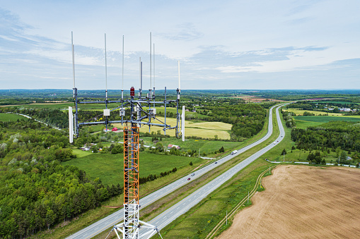 Aerial drone view of a wireless/radio tower near a multilane interstate/highway.
