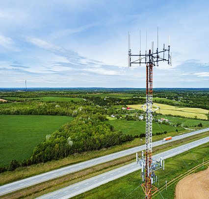 Aerial drone view of a wireless/radio tower near a multilane interstate/highway.