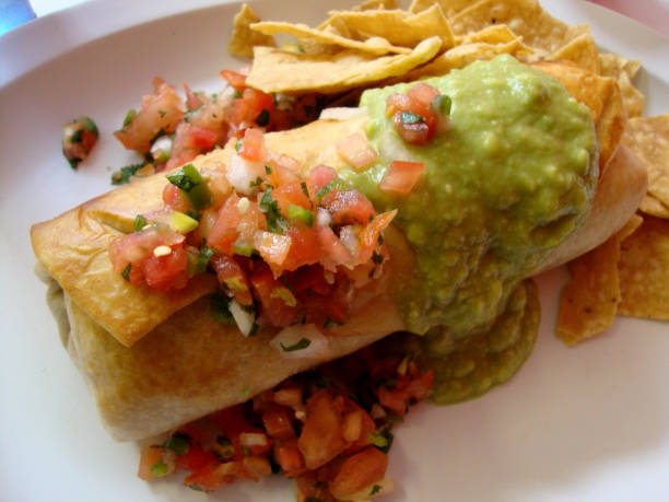 Chimichanga with guacamole and Salsa on top Chimichanga with guacamole, and Salsa on top and a side of chips. burrito stock pictures, royalty-free photos & images