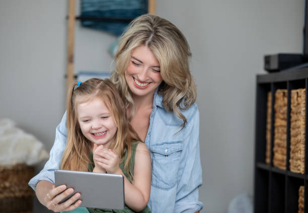 istock Middle aged mother laughing while watching videos on a digital tablet 1321763578