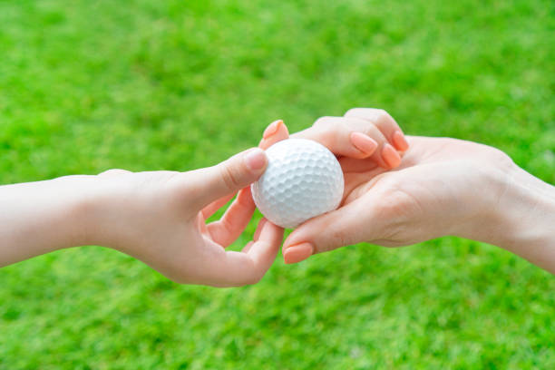 golfkonzept. die hand der frau reicht einem kind einen golfball in die hand. - golf golf club luxury golf course stock-fotos und bilder