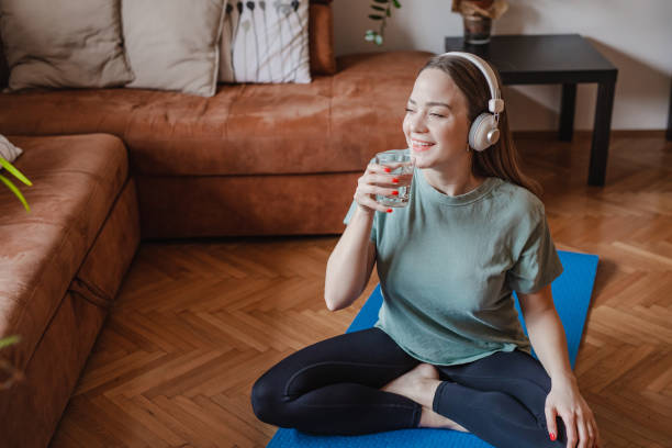 istock Young woman drinks water at home after home exercise 1321766967