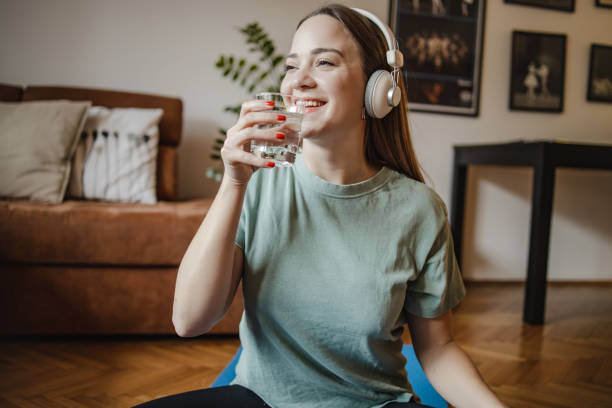 istock Young woman drinks water at home after home exercise 1321767091
