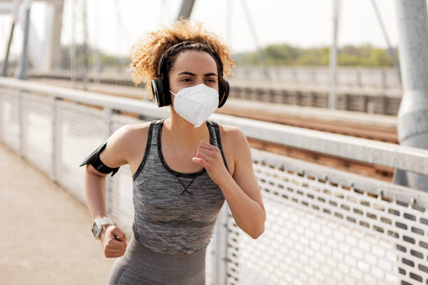 istock Woman jogging on the bridge wearing protective mask 1321768496