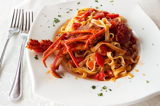 Studio photo of a white plate with spaghetti and lobster tail.