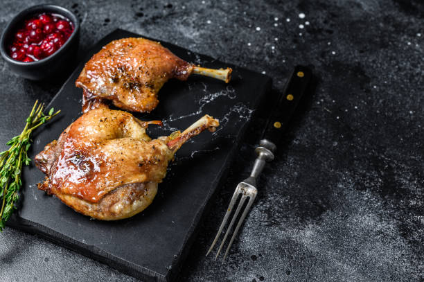 istock Roasted duck leg confit with cranberrie sauce. Black background. top view. Copy space 1321776158