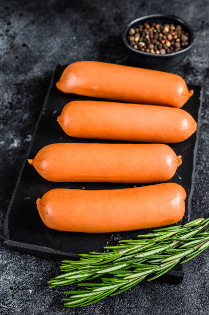 istock Raw barbecue sausages bratwurst on a marble board. Black background. top view 1321776441
