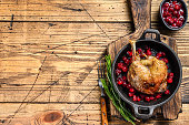 Fried duck leg with cranberrie sauce in a pan. wooden background. top view. Copy space