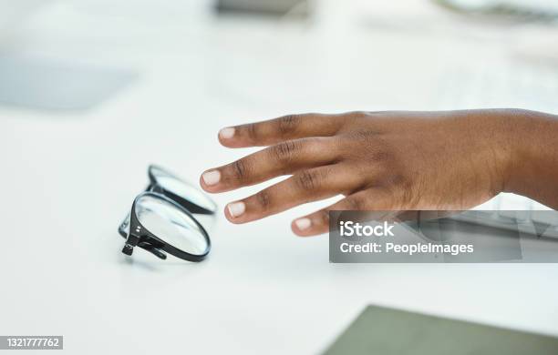 Cropped shot of an unrecognizable businesswoman reaching for her glasses while sitting at her desk