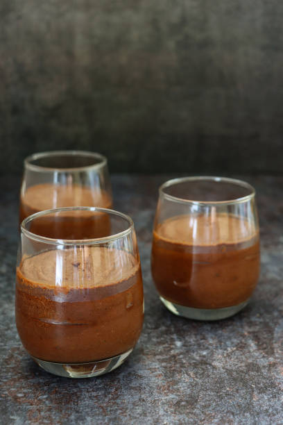 Image of three glasses containing home-made chocolate mousse dessert, dark grey background, focus on foreground