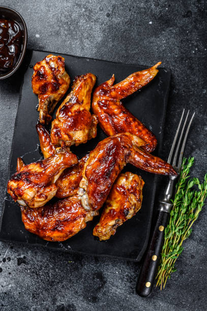 istock Hot Barbecue chicken wings with sauce bbq. Black background. Top view 1321779932