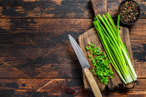 istock Cut Green onions chives on a cutting board. Dark wooden background. Top view. Copy space 1321782425
