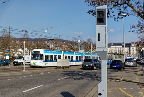 Zurich Switzerland March 10, 2021: stationary radar speed camera, camera in big city with cars and people and streetcar in blurred background, speed controls are important to ensure traffic safety, daytime, sunset