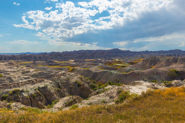 Badlands landscape with sunbeam and dry grass in summer, Badlands national park, South Dakota, USA.