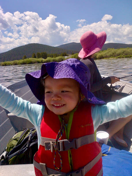 istock Young Girl rows boat while mother fishes 1321810421