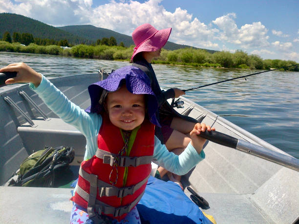 Young Girl rows boat while mother fishes