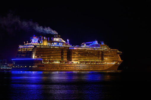 Saint John, NB, Canada - October 13, 2016: The cruise ship Anthem Of The Seas leaves Saint John Harbor at night. Light is reflected in water.