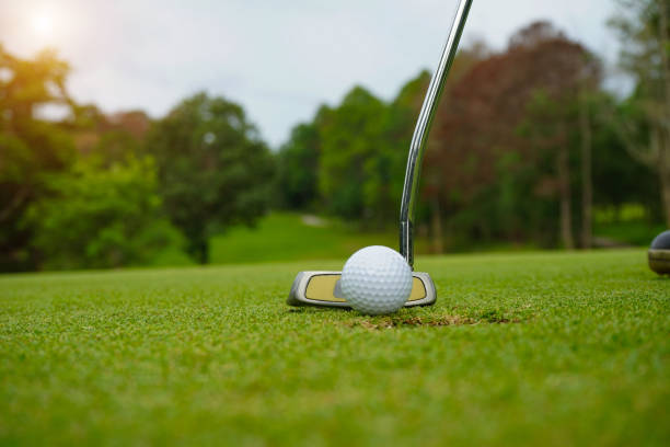 istock Golf player at the putting green hitting ball into a hole 1321830292