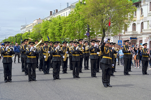 Khabarovsk, Russia - May 30, 2021: Brass band street performance. Russian musicians in uniform are playing wind instruments on the parade. International festival of military bands \