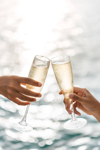 istock Hand holding a glass drinking wine on Sunset sea background. 1321844511