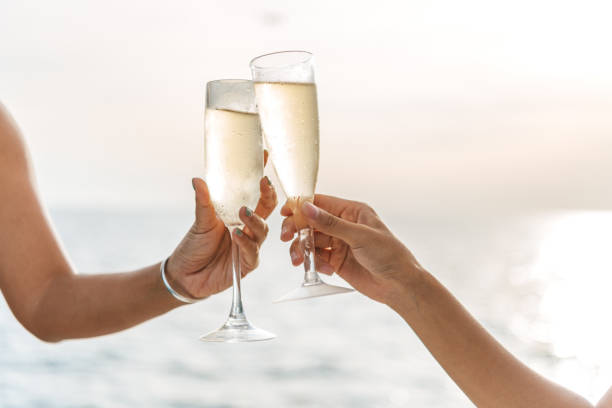 istock Hand holding a glass drinking wine on Sunset sea background. 1321844518
