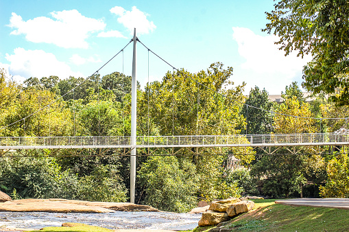 A picture of the walking bridge that  connects the two shores of the Reedy River in Greenville, South Carolina.