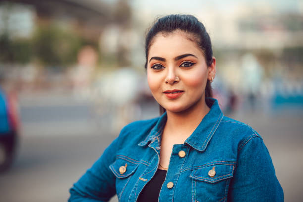 Portrait of young brunette girl in denim shirt Outdoor close up Portrait of young brunette Asian/ Indian girl wearing blue denim shirt and laughing in day light on city street. south asia stock pictures, royalty-free photos & images