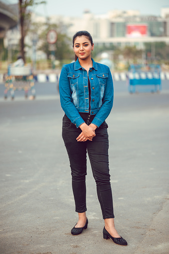 Outdoor Portrait of young brunette Asian/ Indian girl wearing blue denim shirt and laughing. Full length Portrait. fashion model, vertical composition with extra copy space.