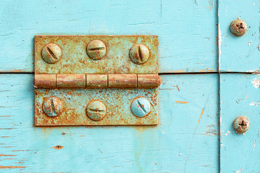 Rusted Hinge and faded blue paint detail. Aged industrial background, graphic reasource.