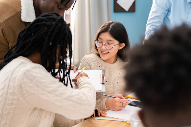 istock Co-workers are sitting in a conference room in an office building, a dark-skinned guy is giving a document to his colleague to sign, another girl with glasses is sitting smiling looking at them 1321853231