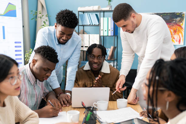 istock Young, talented foreigners, future business partners discuss work strategy, debate company structure, brainstorm, take notes while sitting around a wooden table 1321853449