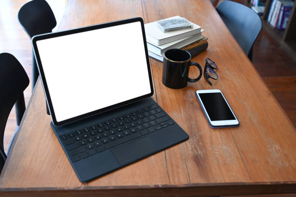 istock Mock up computer tablet, smart phone, coffee cup  and books on wooden table. 1321856633