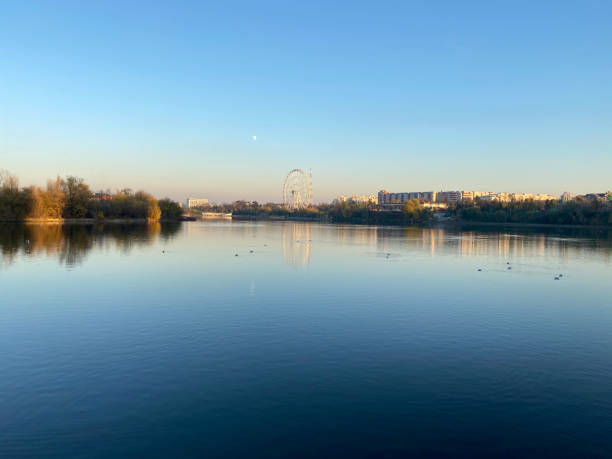 istock Amusement park, city and moon reflection on a lake 1321858989